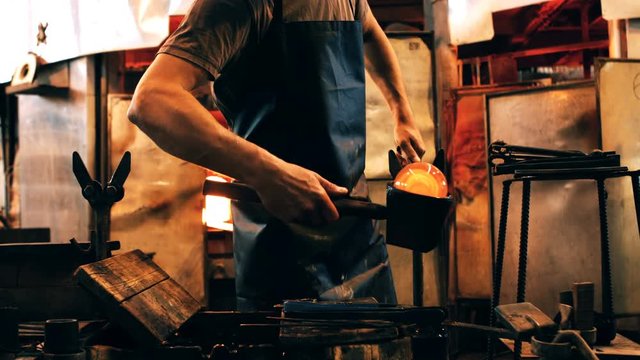 Mid section of glassblower shaping a molten glass