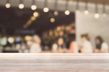 Wood table top and blurred bokeh cafe and coffee shop interior background with vintage filter - can used for display or montage your products.