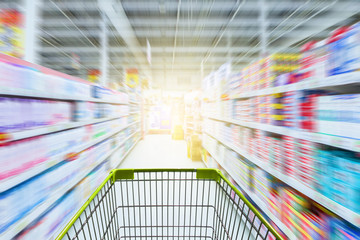 Supermarket aisle with empty green shopping cart