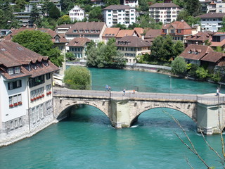 Fototapeta na wymiar Stony bridge over clean alpine Aare river in city of Bern