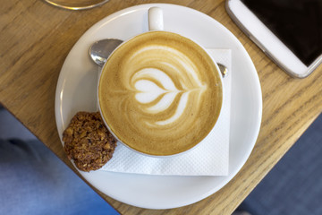 cup of coffee with spoon and cookie on table