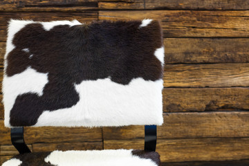 Cow skin chair  and old wood wall background.