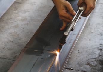 Closeup metal cutter, steel cutting with acetylene torch, industrial worker on manufacturing area.