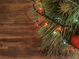 Green Christmas tree decorated with toys and garland with led lights at wooden table. Festive green spruce. Flat lay with copy space, top view.