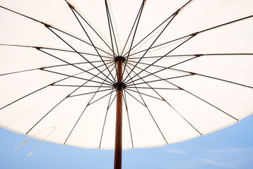 White beach umbrella on a sunny day against sky background.