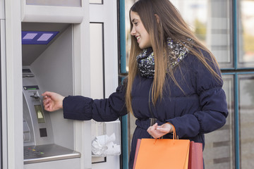 Girl with shopping bag on ATM