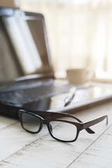 Eyeglasses on office desk with laptop at workplace