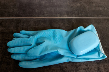 Blue rubber gloves and soap on a dark background. 
