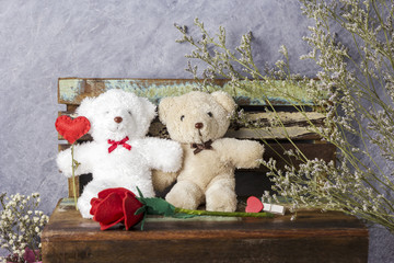Love concept of couple teddy bear with red heart and rose on old chair for valentines day and wedding