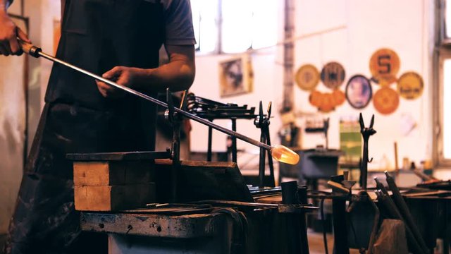 Mid section of glassblower shaping a molten glass