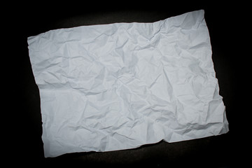 crumpled white paper on black background.