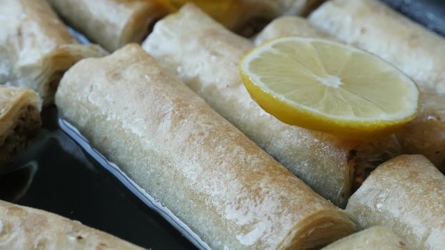 Turkish phyllo pie filled with walnuts 4K 2160p 30fps UHD panning footage - Close-up of sweet syrup of lemon on filo dough rolls 3840X2160 UltraHD pan video 