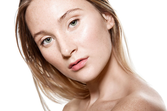 woman with freckles on her face with a light sensitive skin. Portrait with bare shoulders on a white background