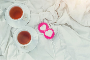 Breakfast in bed in Valentines day. Cup of tea and sweet candies. Love or holiday concept