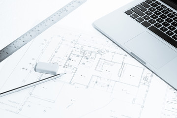 Pen, metal ruler, rubber and notebook over house construction bl