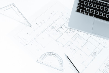 Pen, drawing rulers, and notebook over house construction bluepr