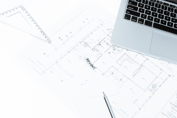 Pen, drawing rulers, and notebook over house construction bluepr