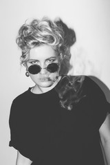 Stylish fashion sexy blonde bad girl in a black t-shirt and rock sunglasses covered with cigarette...
