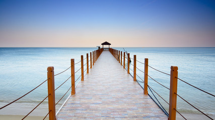 Fototapeta premium Beautiful sunset over wooden jetty with silhoutte of man fishing