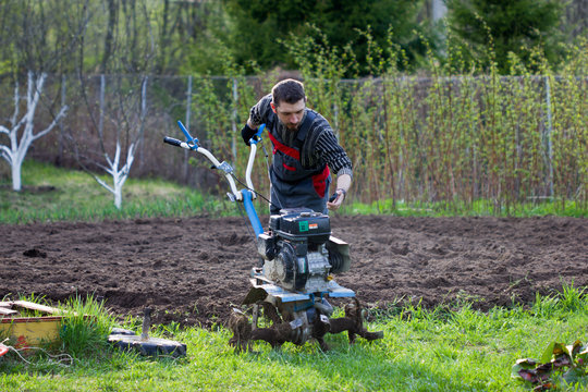 man cultivates the land with the cultivator