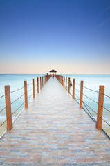 Beautiful sunset over wooden jetty with silhoutte of man fishing