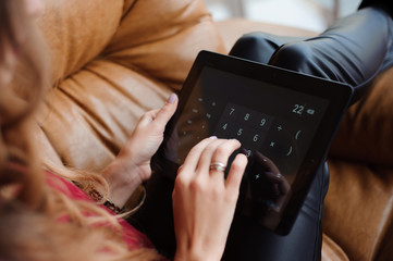 Close-up of the hands of a young woman working with the tablet a