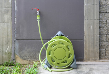 water tap with green rubber tube roll up in the garden