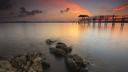 Obraz premium Beautiful sunset reflections with silhouette peoples on the jetty