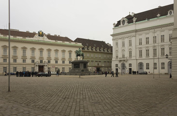 Fototapeta na wymiar Inside Hofburg complex in Vienna, square with equestrian statue and people around