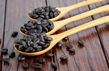 Fresh coffee beans on wooden spoon.