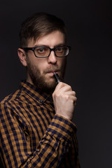 man with a beard wearing glasses on black background smoke Vape. large portrait of . electronic cigarette. E- for vaping. Popular devices  the year - modern device. Stop smoking,