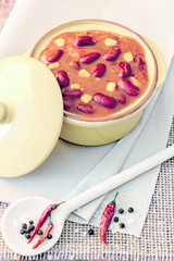 Chili im Topf mit getrockneten Chilis und Pfeffer und Salz auf Holzlöffel