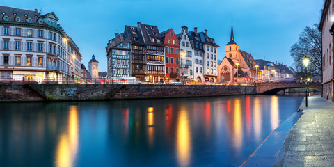 Picturesque panorama of quay and church of Saint Nicolas with mirror reflections in the river Ile during evening blue hour, Strasbourg, Alsace, France - obrazy, fototapety, plakaty