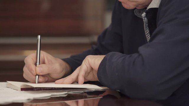 Focus on old man 's hand writing on notepad
