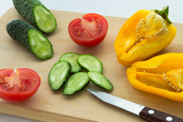 Sliced tomatoes, cucumbers, peppers and knife on the table
