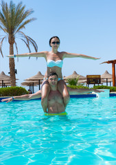 Naklejka premium Young woman sitting on man's neck while they doing aqua fitness