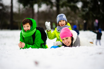 Fototapeta na wymiar Young woman and two of her sons cheerfully spend time in the park in winter day.