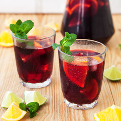 Fresh sangria in glasses with ingredients - orange, lemon and lime slices and mint