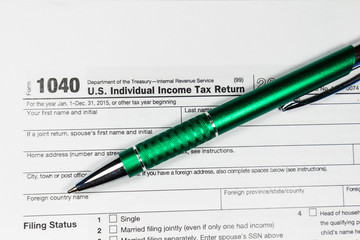 Business woman fills the tax form 1040 with pen and calculator