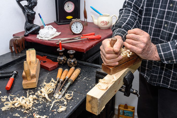 old man hand planers wood in the workshop