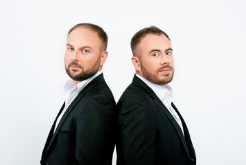 portrait of two men in black suits on white background