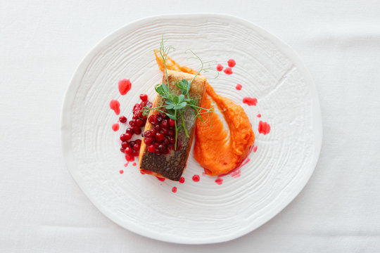 Fried salmon steak with pumpkin puree, red berry sauce and herbs