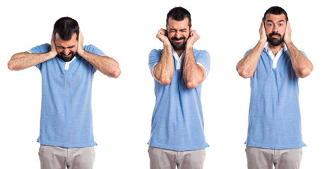 Man with blue shirt covering his ears