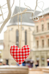 heart made by hand hanging on a white branch of tree. Valentines day. Hand made embroidered decoration.