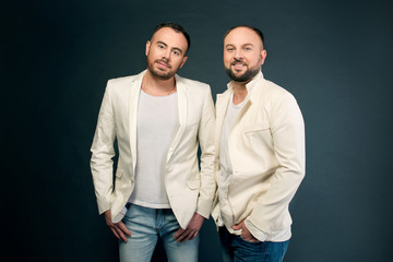 Portrait of two men in white suits on dark background