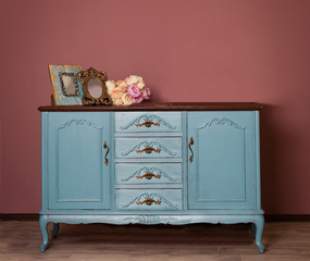 Vintage blue wooden dresser, tender bouquet and two frames. Blue and brown vintage interior. Brown...