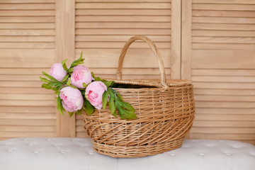 Fototapeta na wymiar Peony flowers in a basket on a wooden background