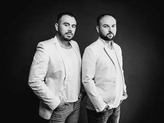 Fototapeta na wymiar Portrait of two men in white suits on dark background
