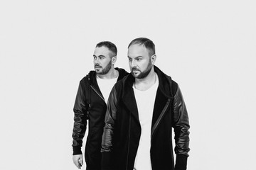 Portrait of two men in black jackets and hats on white background