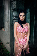 portrait of a girl in a pink dress and a black veil near the tomb in the cemetery